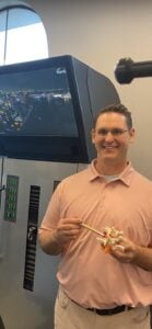 Chiropractor pointing to spine model in front of DRX9000 spinal decompression table in Frisco clinic